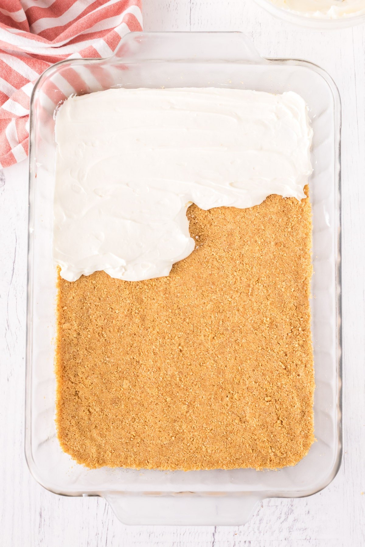 Cream cheese being added to graham cracker crust