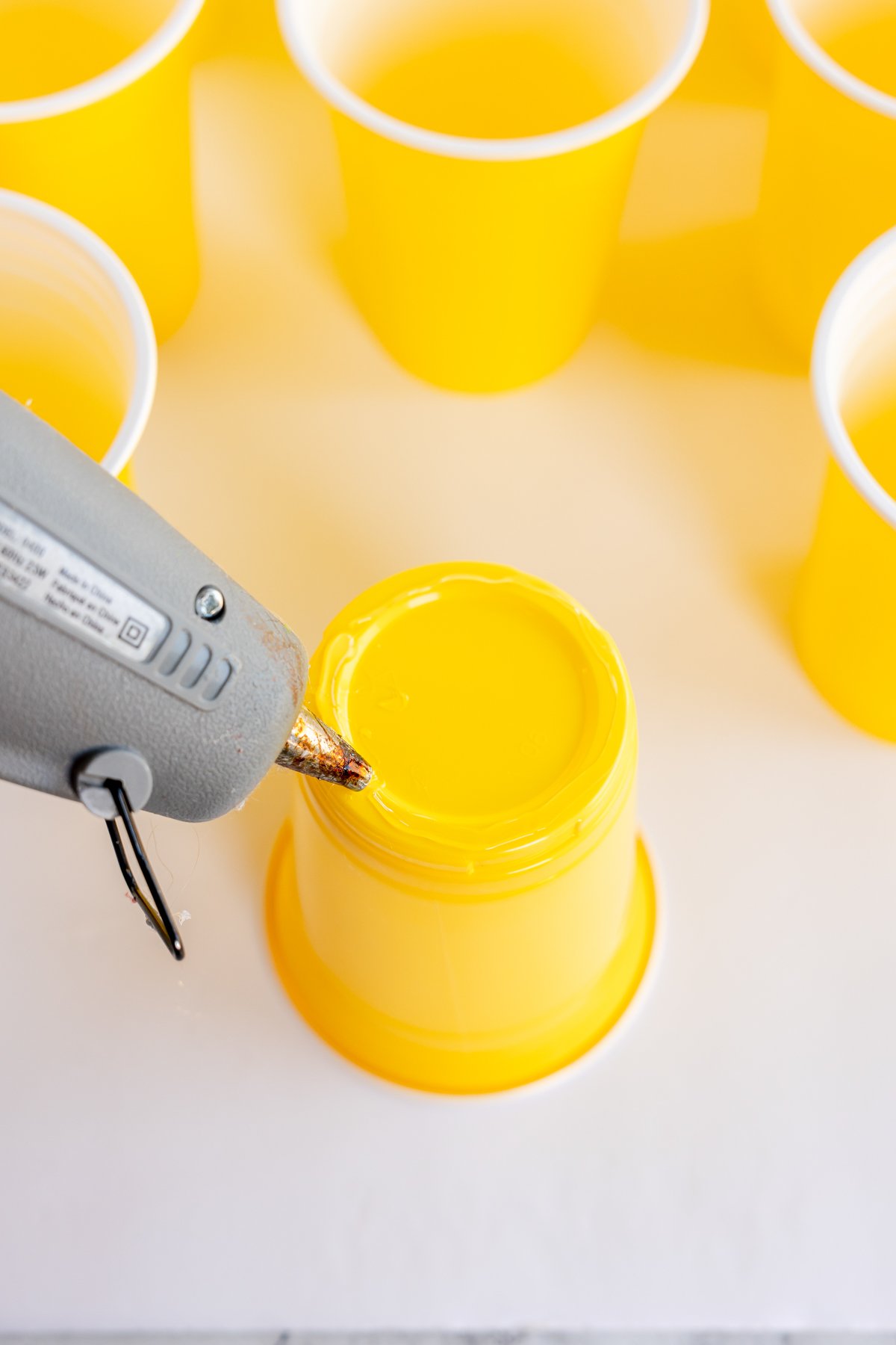 hot gluing the bottom of a yellow cup