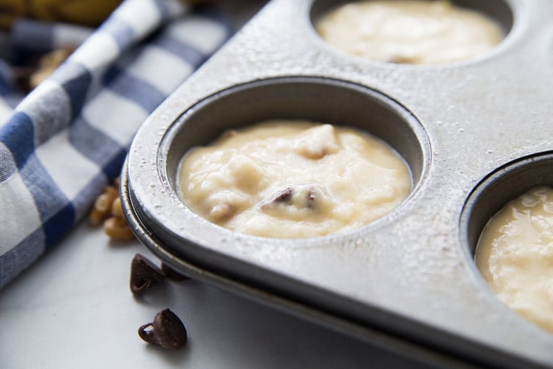 Putting batter into muffin cups for banana chocolate chip muffins