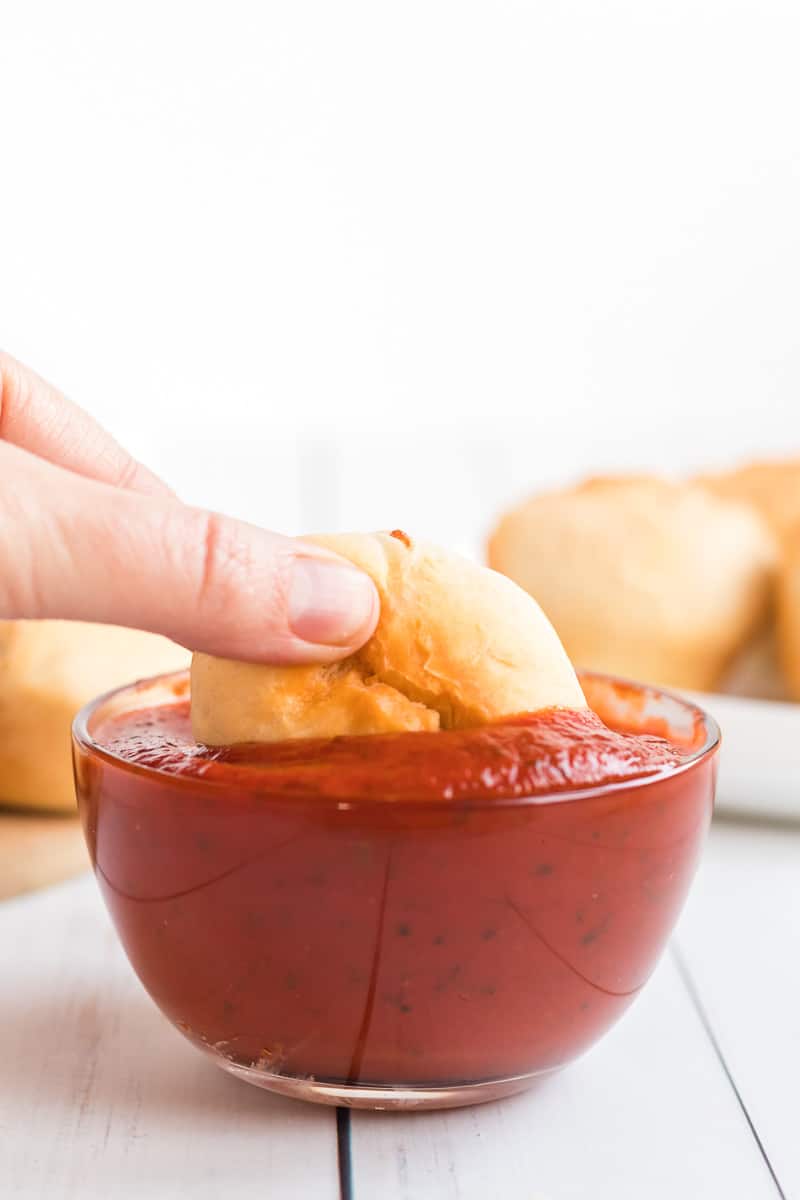 Pepperoni calzone being dipped into sauce