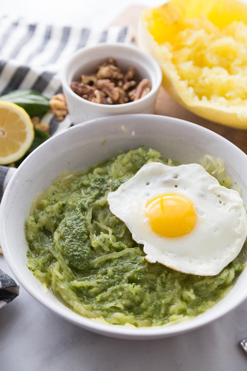 A white bowl with spaghetti squash pesto and a fried egg on top