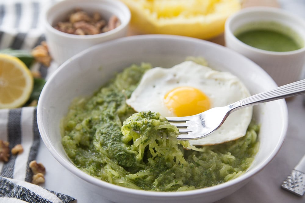A fork full of spaghetti squash pesto with a fried egg in a bowl