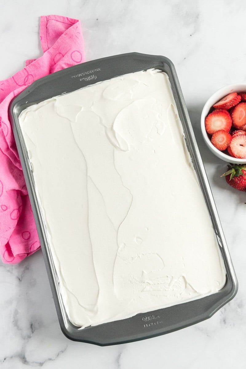 Strawberry poke cake topped with whipped cream