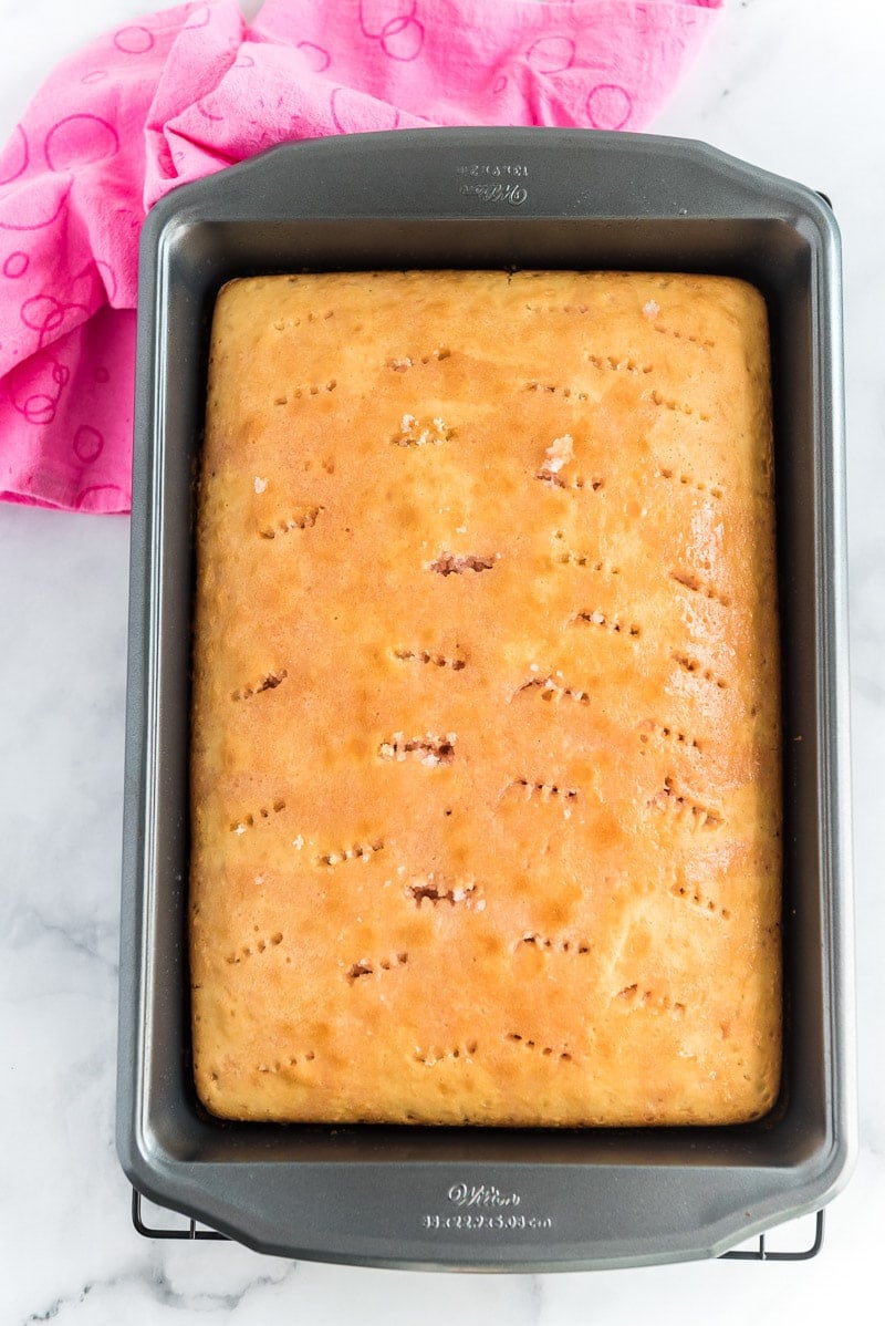 Holes poked into a strawberry poke cake