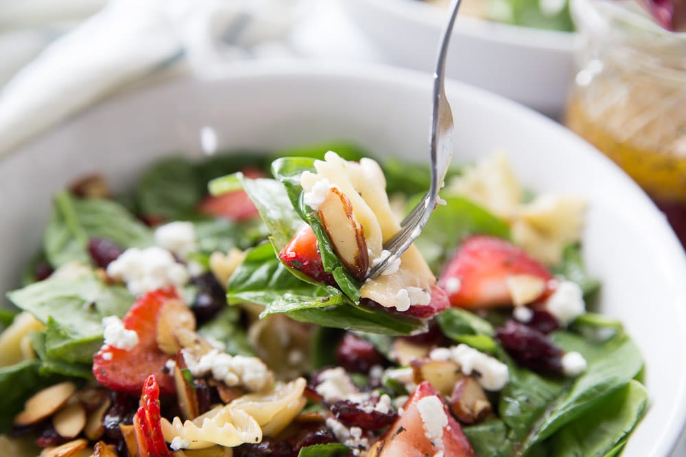 A fork full of strawberry spinach salad