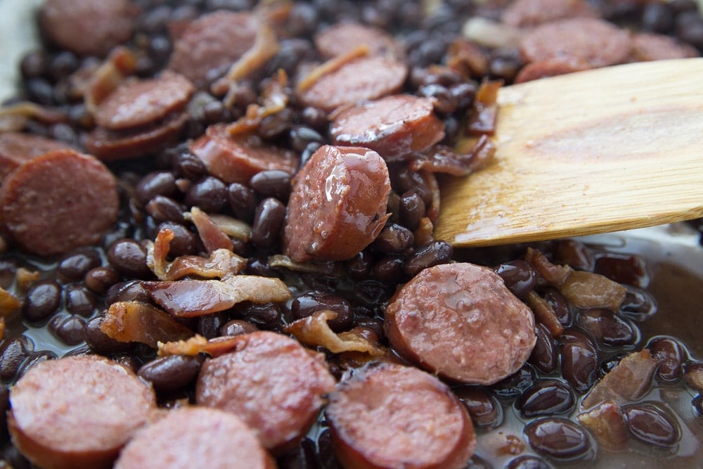 Spoon stirring pan full of feijoada