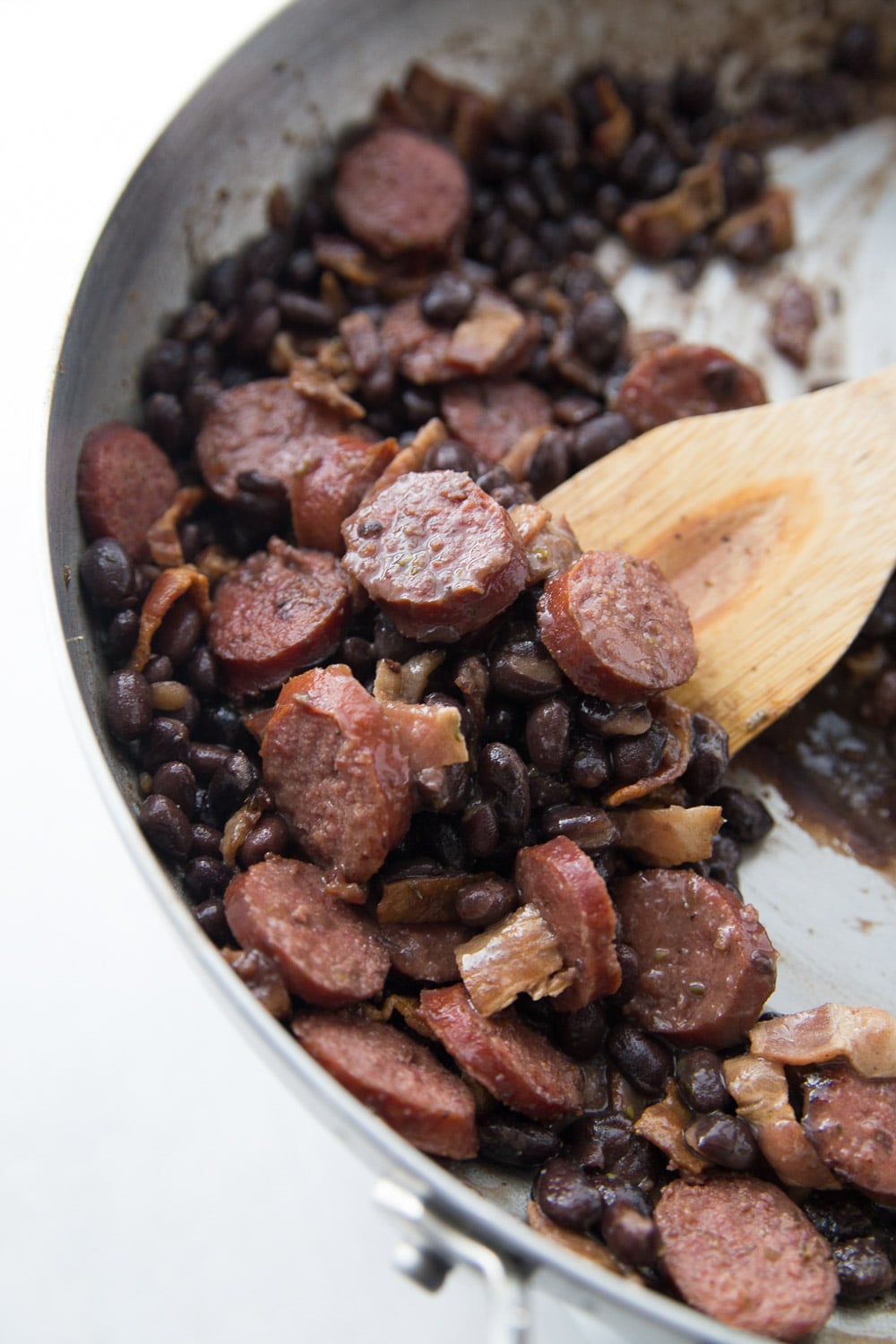 Wooden spoon stirring pan full of feijoada