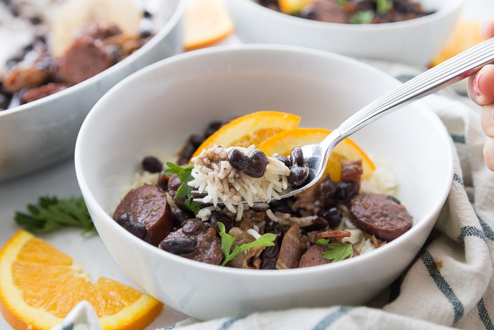 Spoon full of feijoada above a bowl full of feijoada