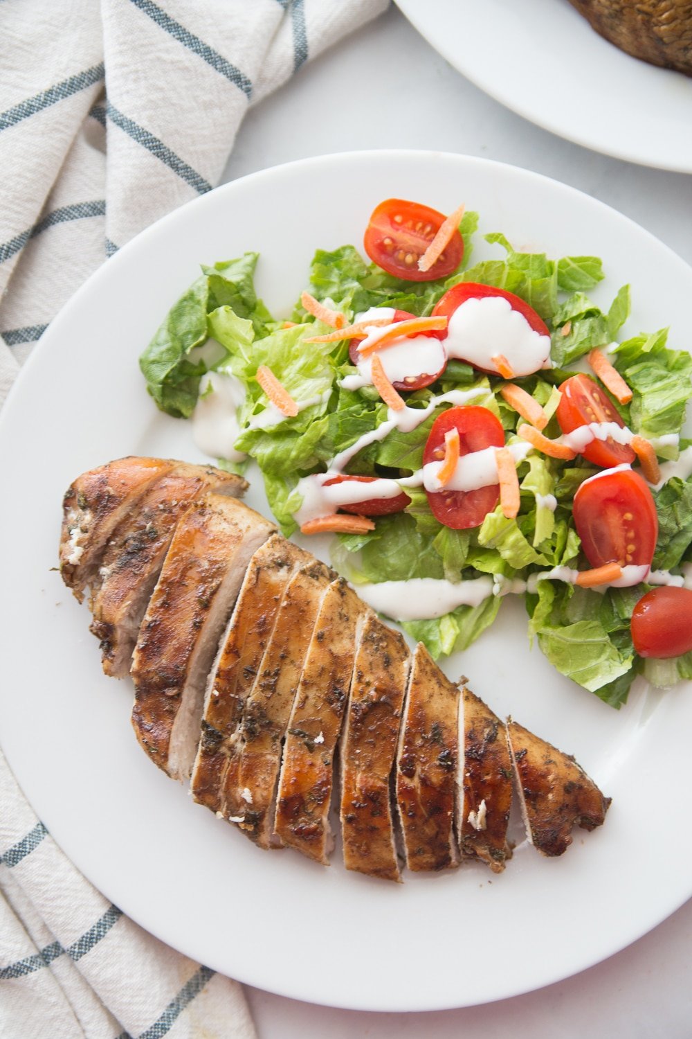 Sliced balsamic grilled chicken on a plate with salad