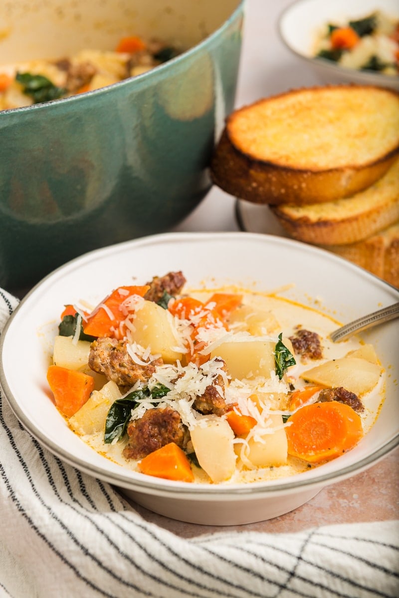 white bowl with zuppa tosacana soup and some bread in the background