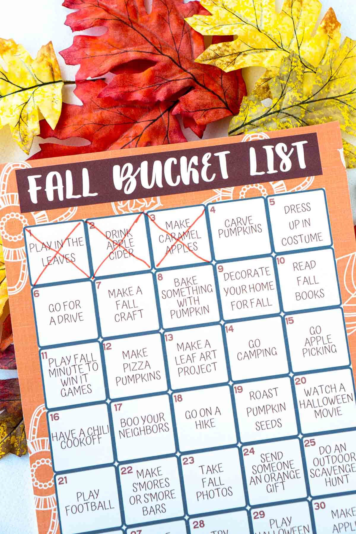 A fall bucket list with three items marked off on top of fake leaves