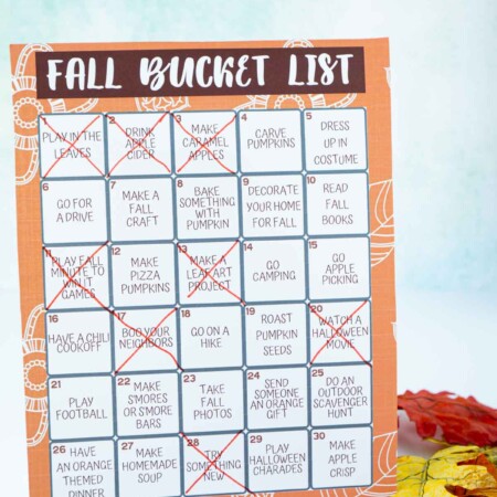 A fall bucket list with items crossed off surrounded by fake leaves