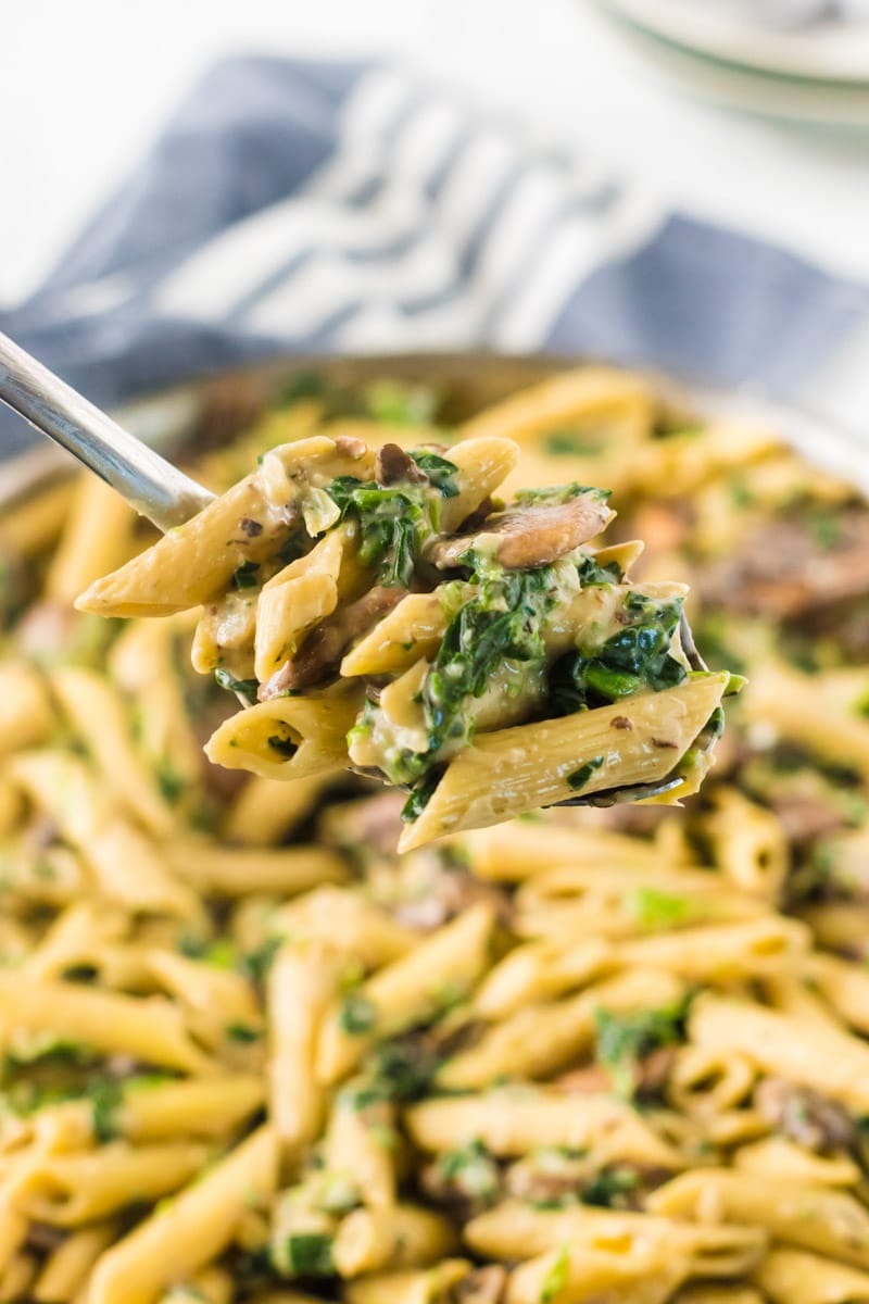 Fork full of spinach and artichoke pasta