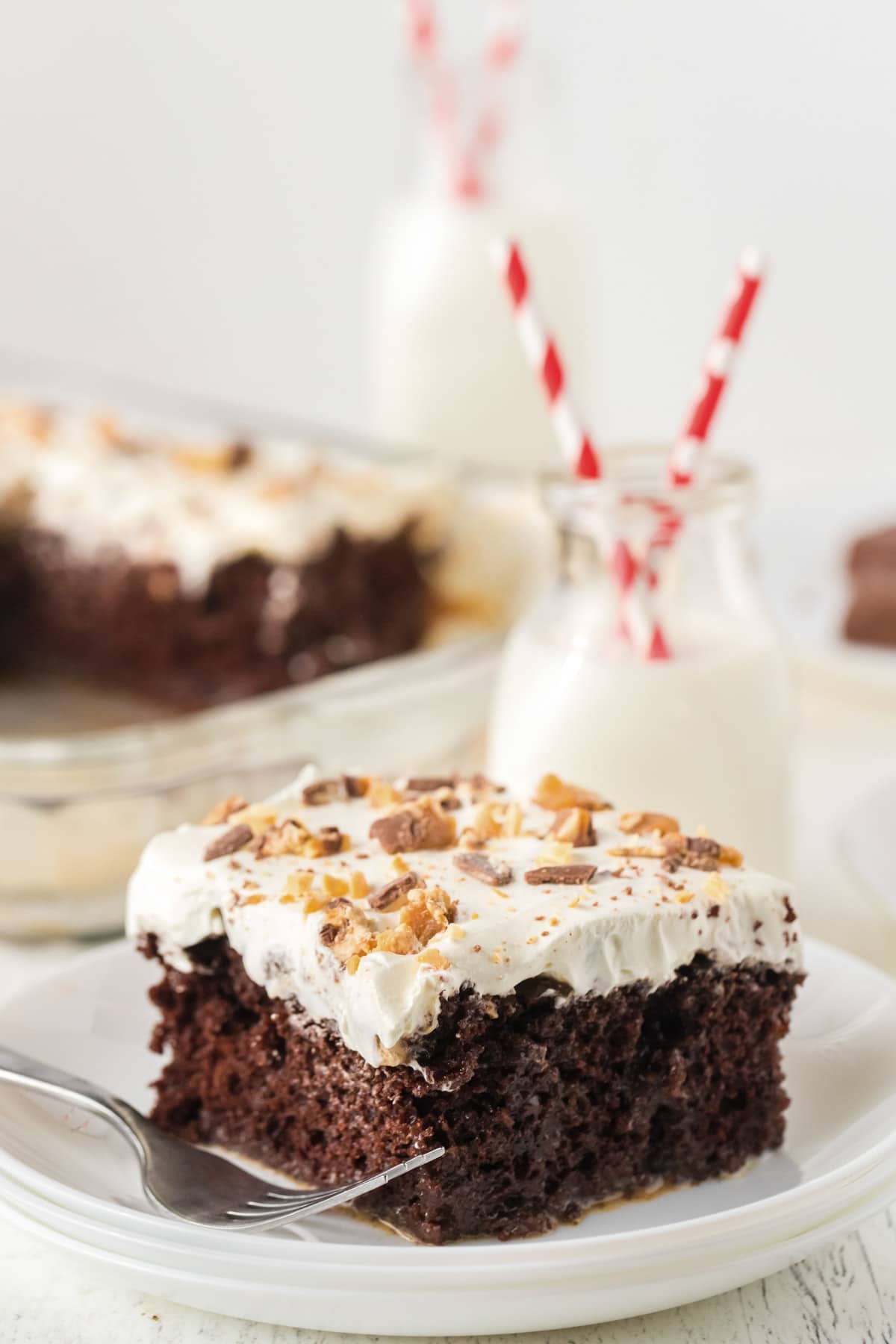 Snickers poke cake on a white plate with a fork