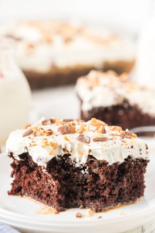 Piece of Snickers poke cake with a bite taken out of it