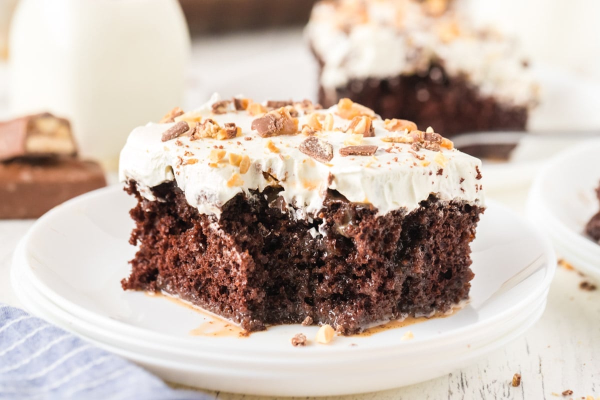 Close horizontal picture of Snickers poke cake with a bite taken out