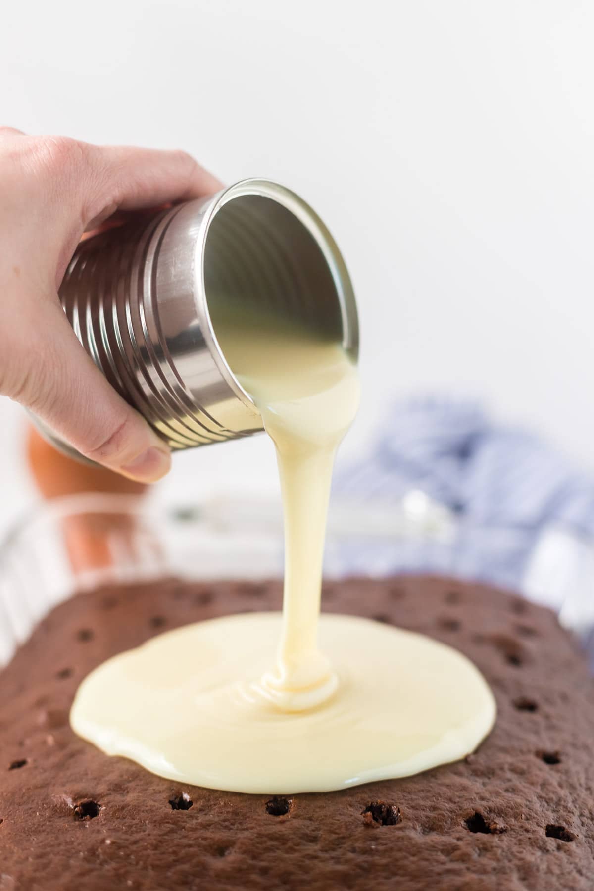 Pouring condensed milk over chocolate cake