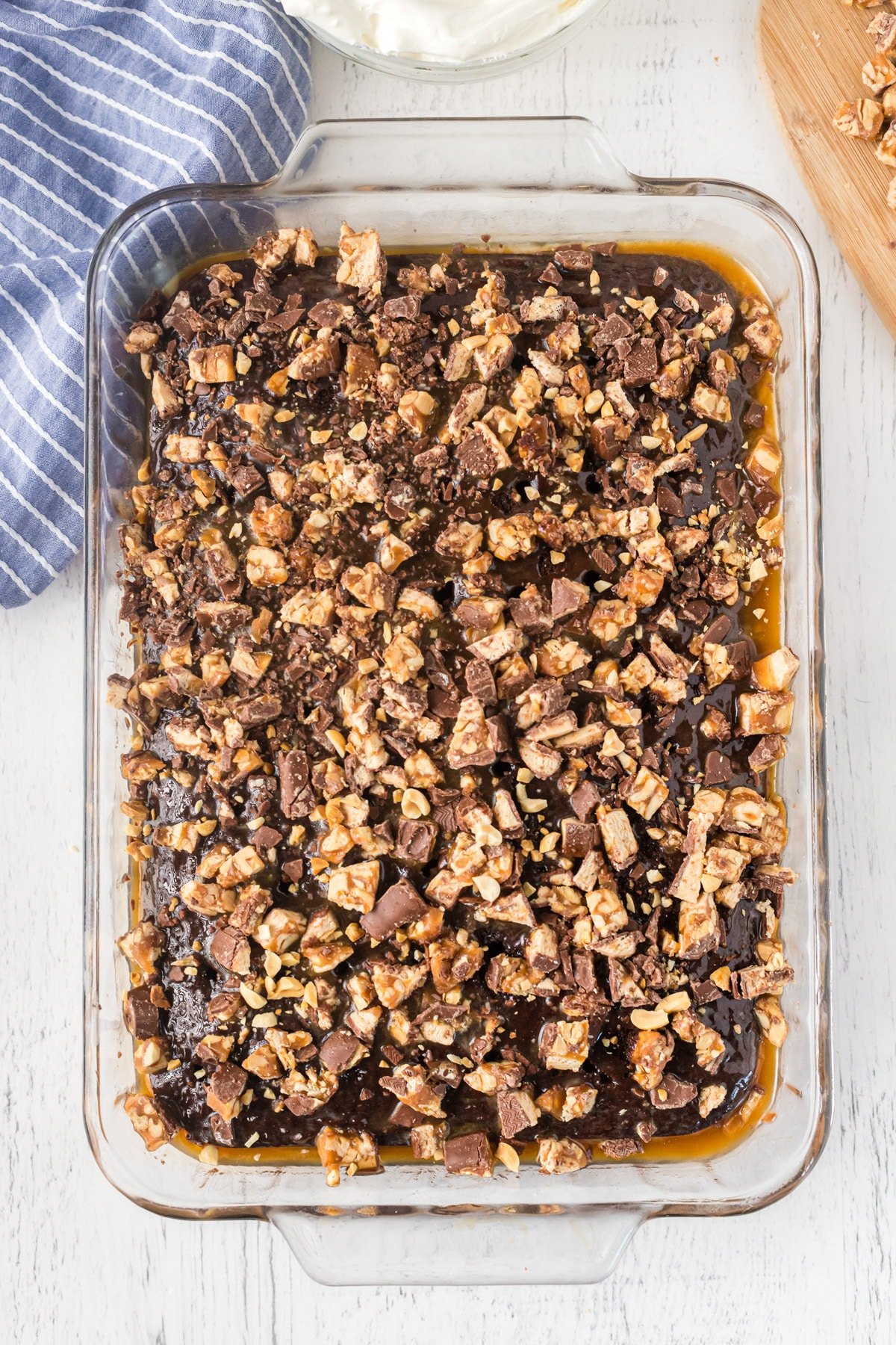 Adding chopped Snickers to Snickers poke cake