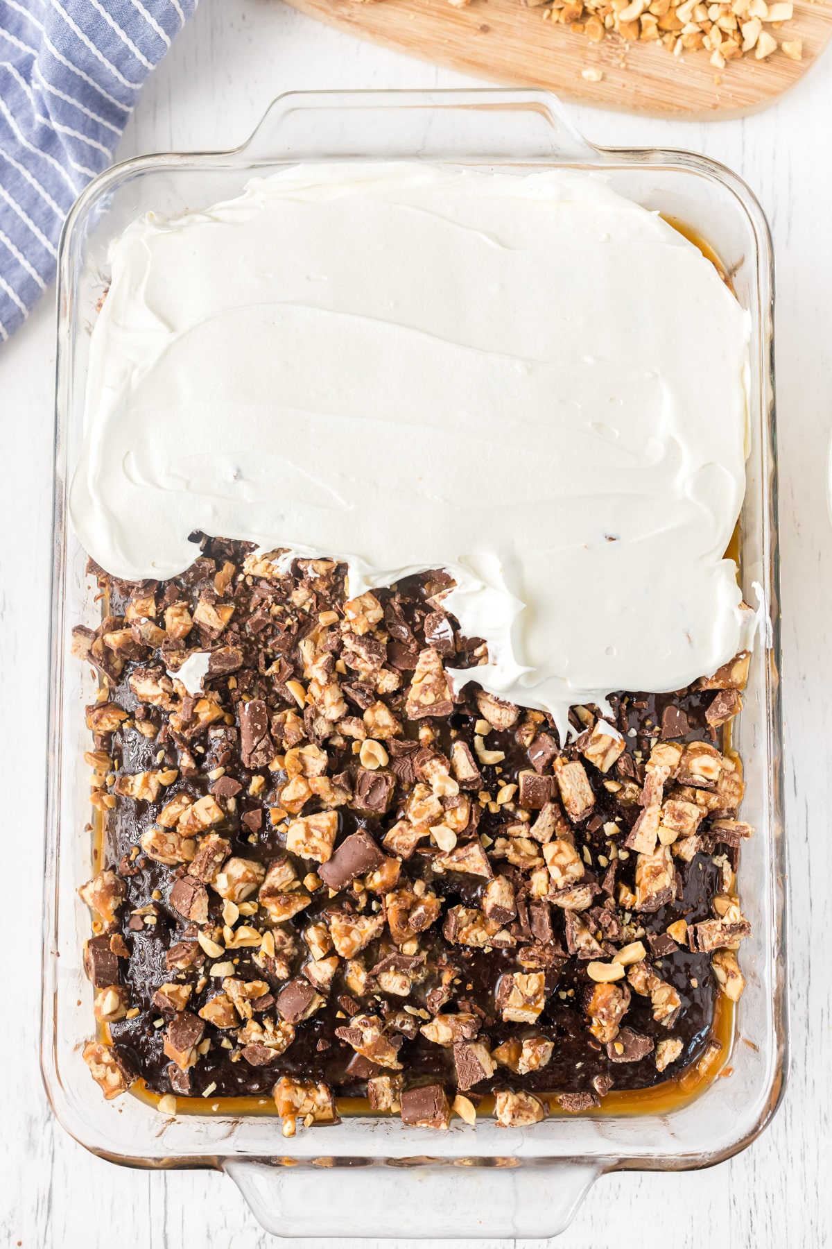 Topping Snickers poke cake with whipped cream
