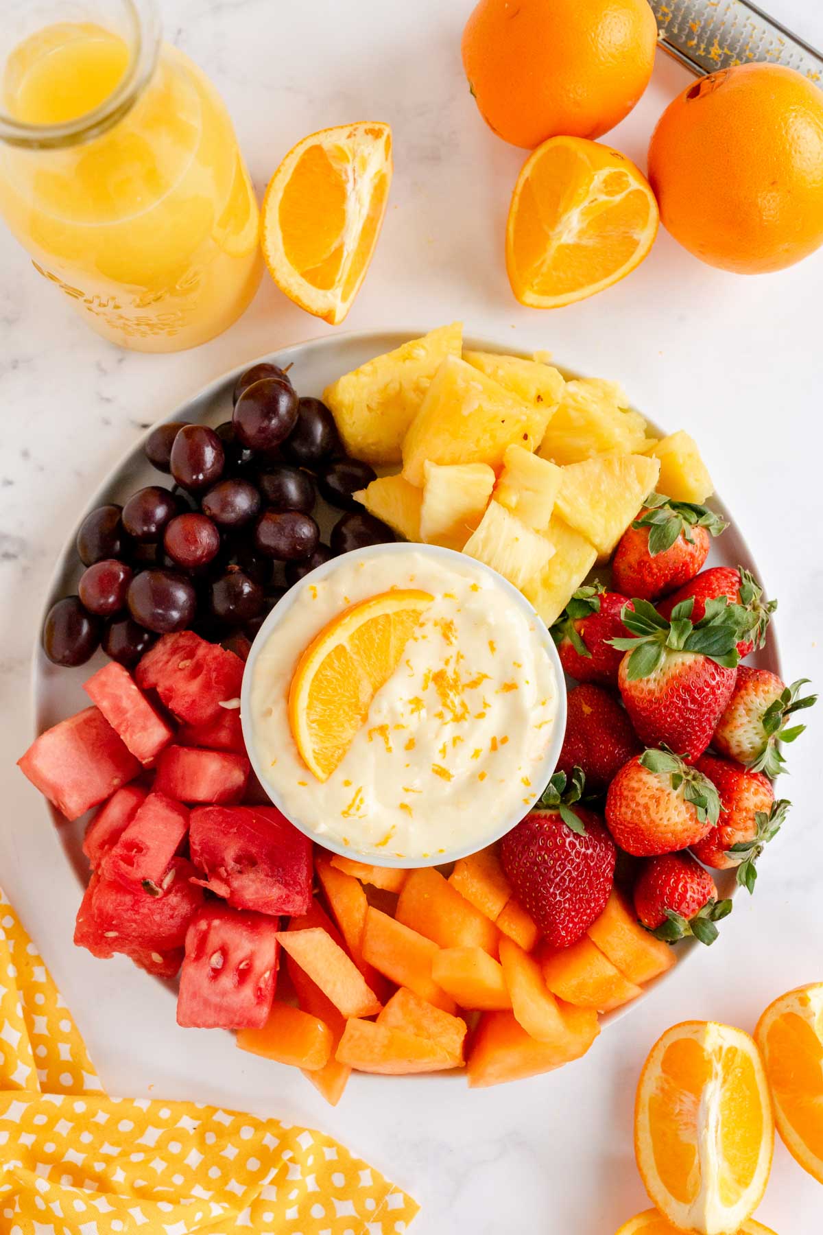 tray of fruit with a bowl of fruit dip in the middle