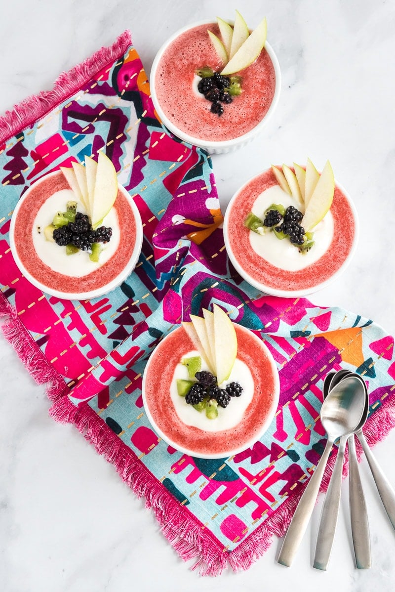 Four bowl of chilled strawberry soup and spoons