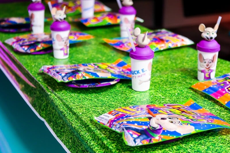 A table set with collectible cups for a Chuck E Cheese party