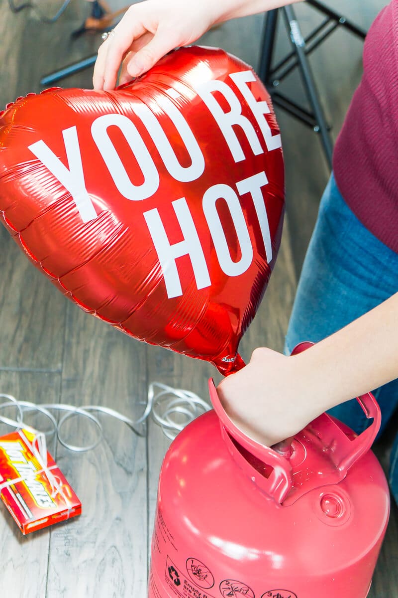 Forget traditional candy grams! This year for Valentine's Day, kick old-school candy grams up a notch with this fun DIY balloon candy gram idea! With tons of clever candy bar sayings and simple instructions, this makes the best gift for boyfriend or any valentine! Love the list of other Valentine's Day gifts for him at the bottom too!