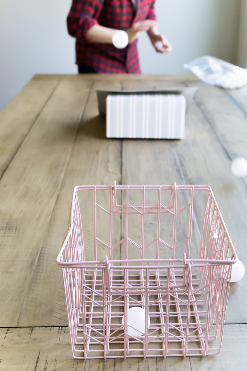 girl rolling ping pong balls over a ramp into a basket
