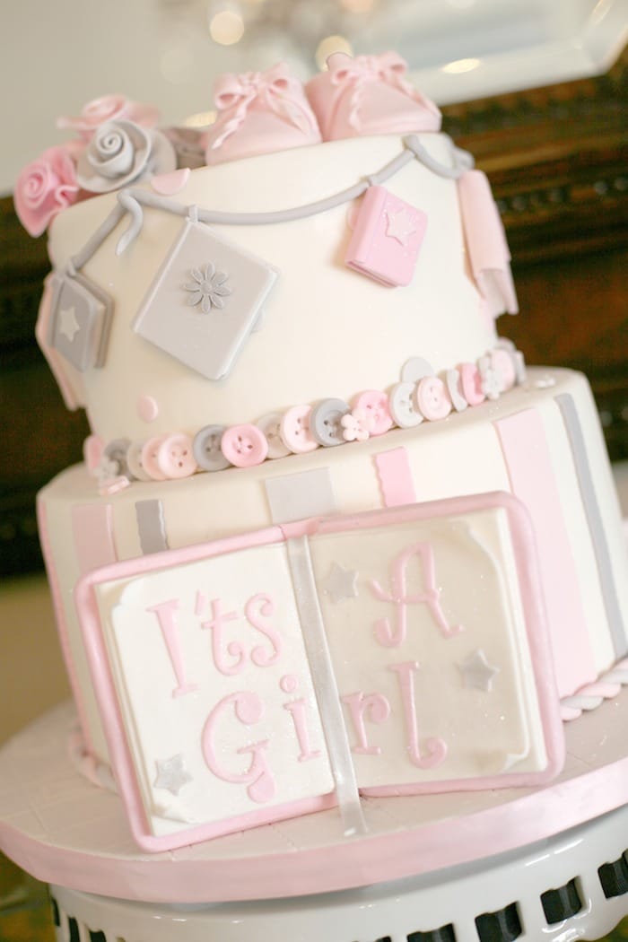 A white it's a girl cake with a cake book in front