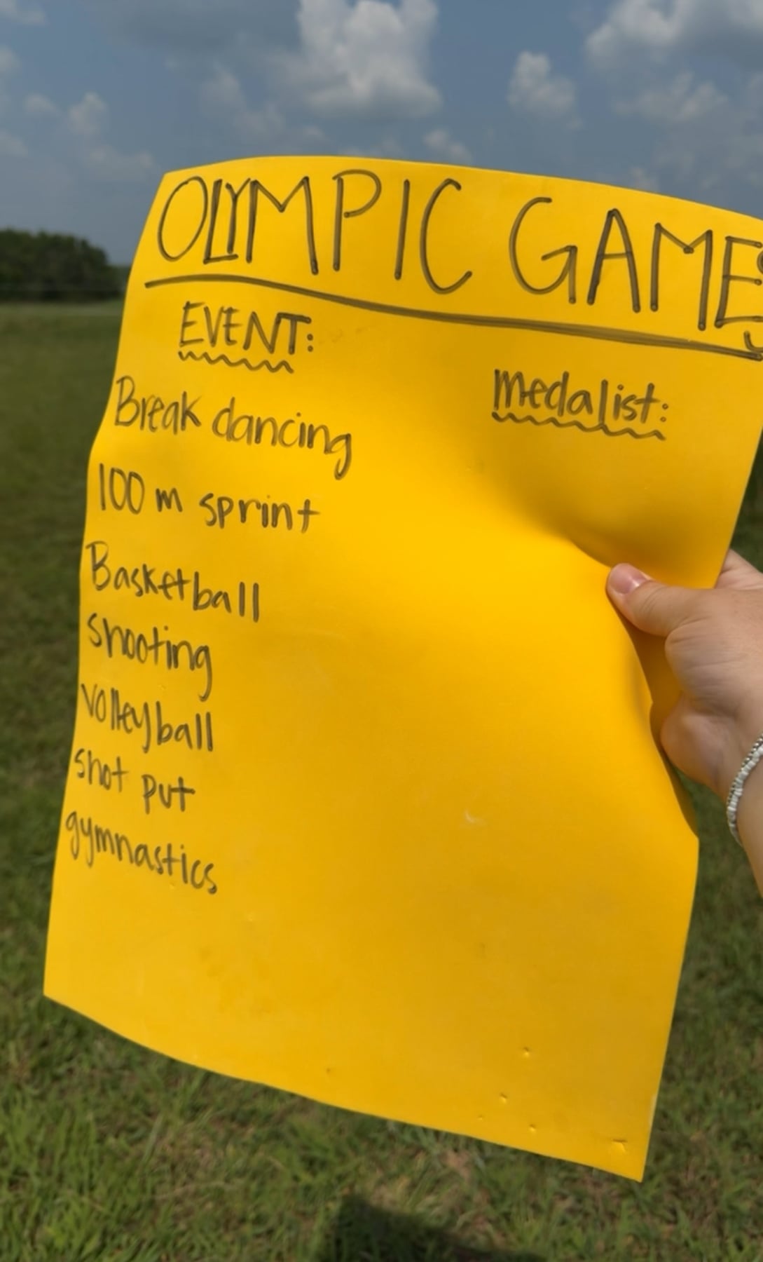 hand holding a yellow piece of paper with olympic games