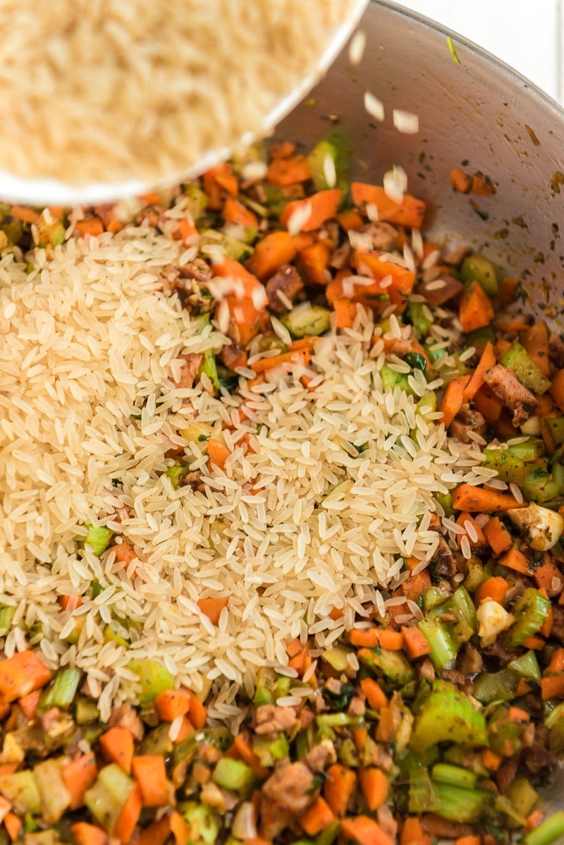 Adding rice to sausage jambalaya