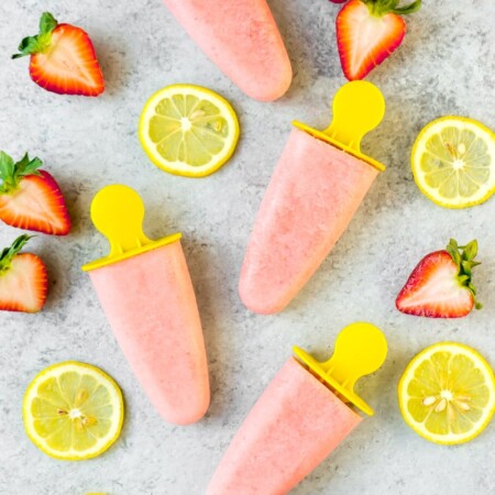 Strawberry lemon popsicles shown with fresh fruit slices