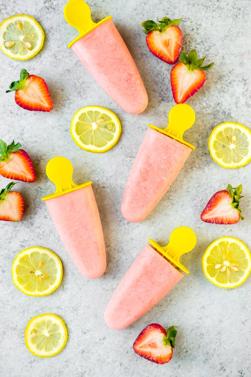 Strawberry lemon popsicles shown with fresh fruit slices