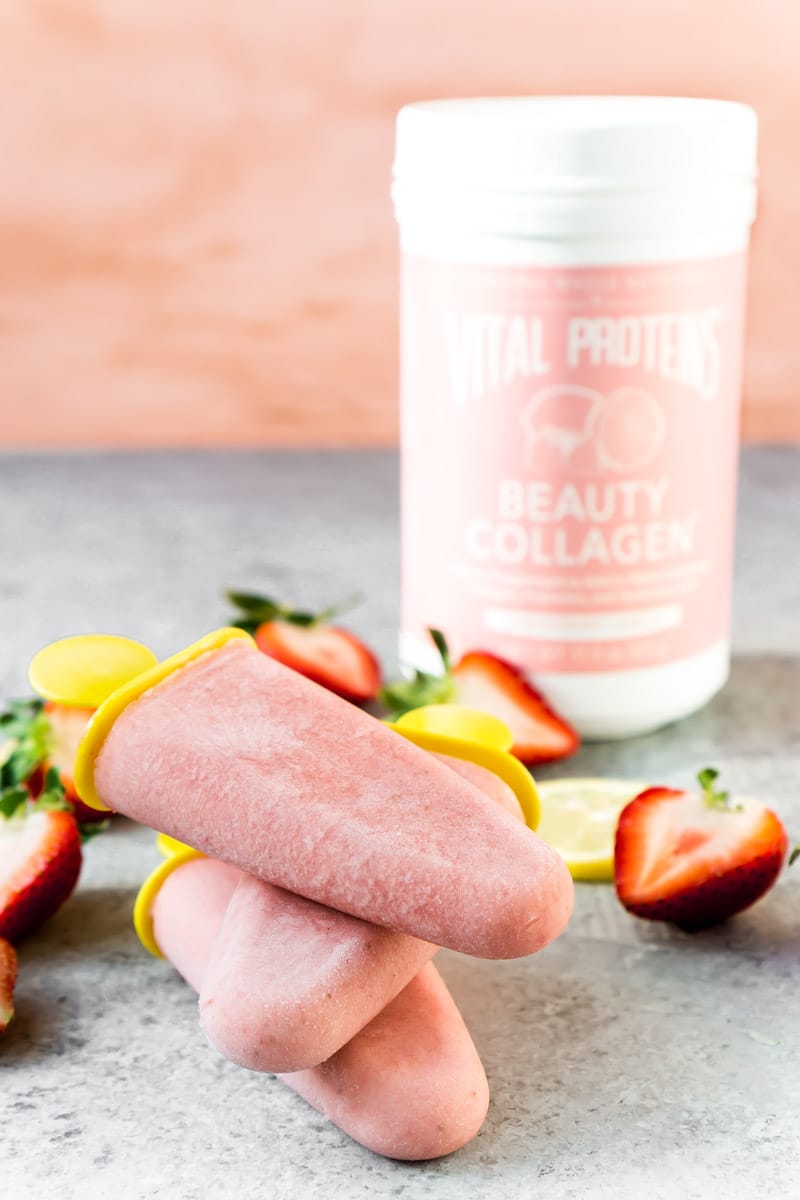 Strawberry popsicles stacked on top of each other with Vital Proteins collagen peptides in the background