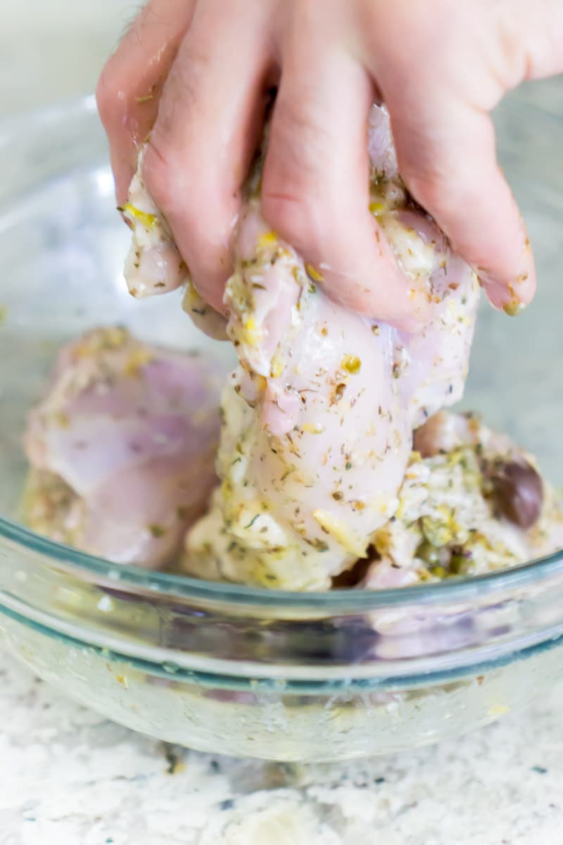 Dipping chicken into a Greek chicken marinade for a lemon chicken recipe