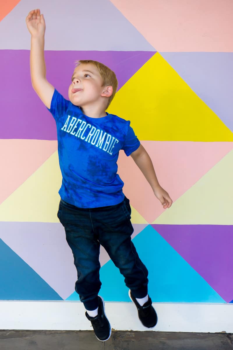 Kid jumping in front of a wall while getting ready for kindergarten