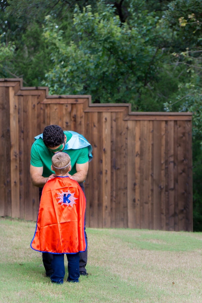 Dad helping son put on DIY superhero costume