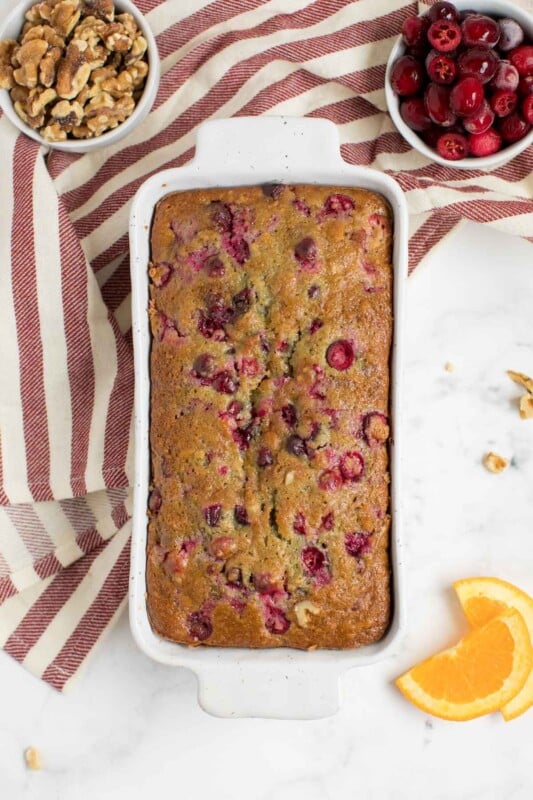 A loaf of cranberry orange bread in a white bread pan