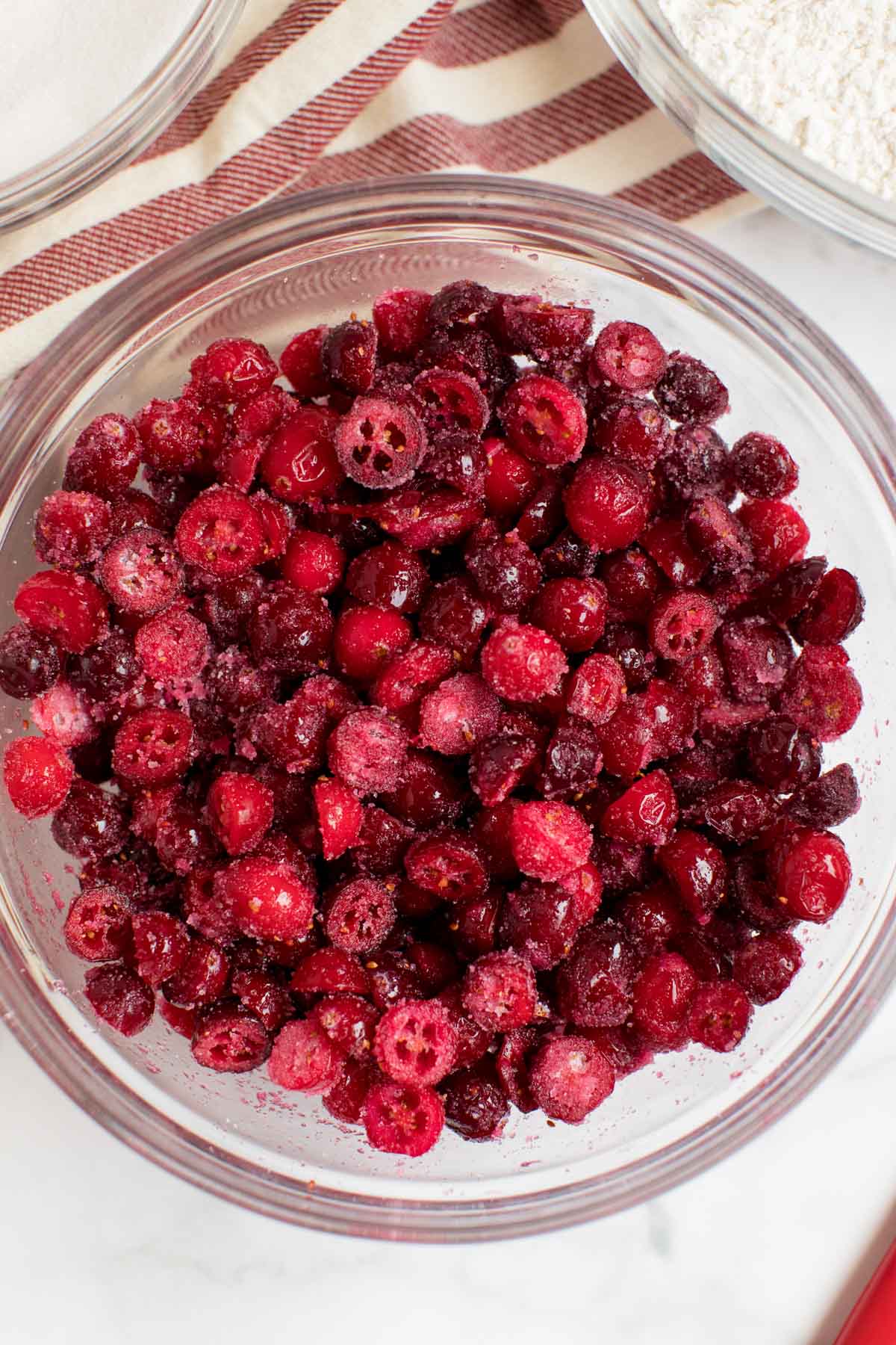 Chopped cranberries in a large glass bowl with sugar