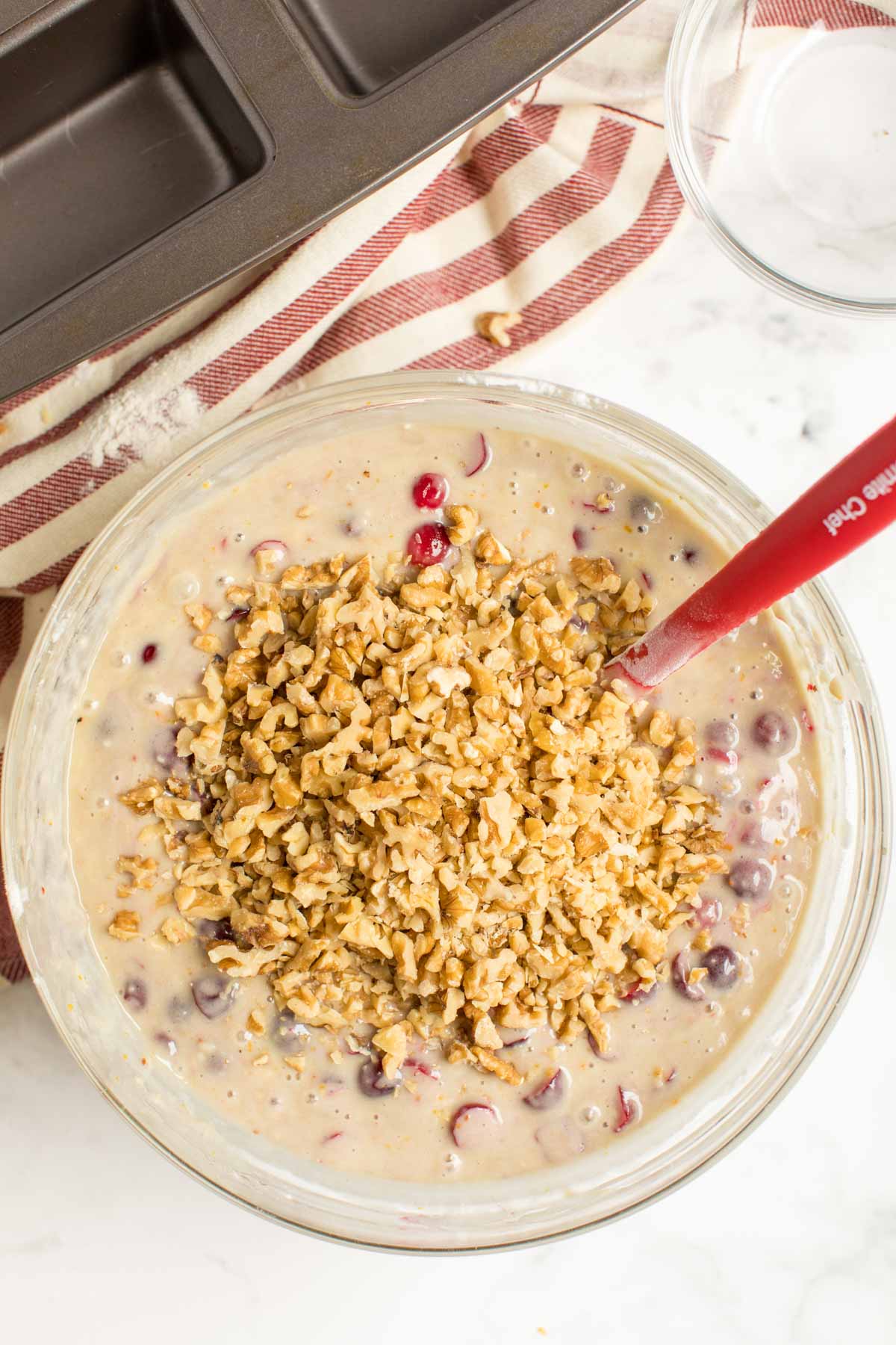 Glass bowl with nuts, cranberries, and cranberry orange bread batter