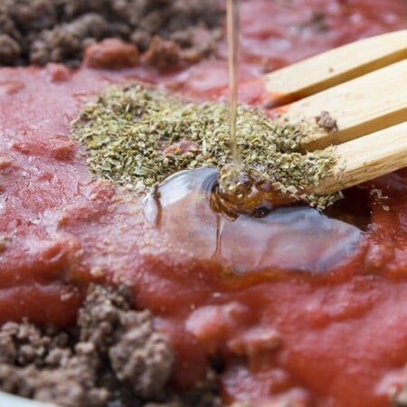 Spices and honey being poured into the best spaghetti sauce recipe