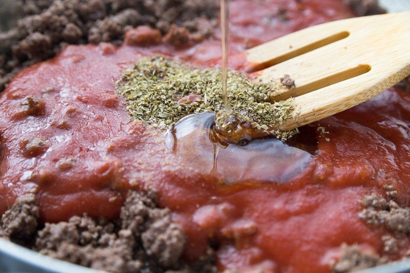 Spices and honey being poured into the best spaghetti sauce recipe