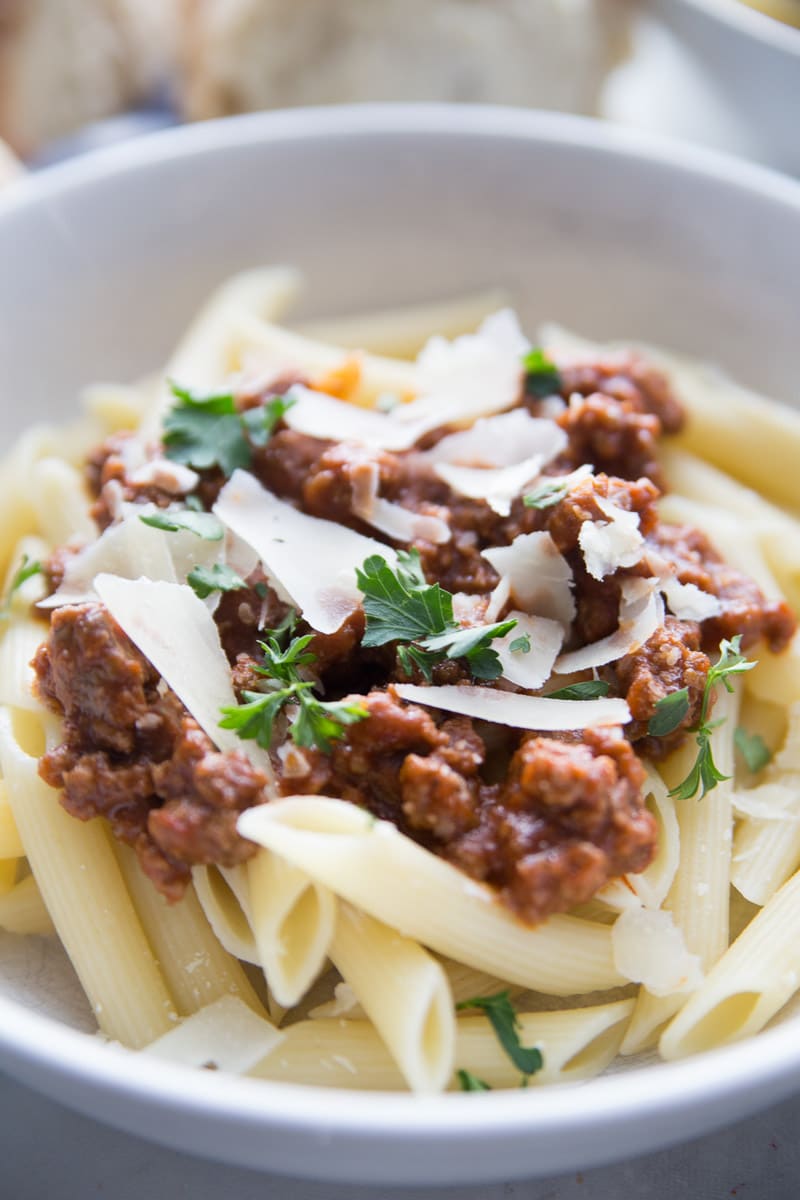 A bowl full of pasta topped with homemade spaghetti sauce and parmesan cheese