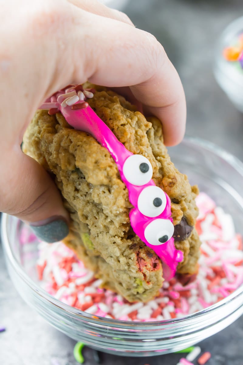 A monster cookie sandwich being dipped in sprinkles