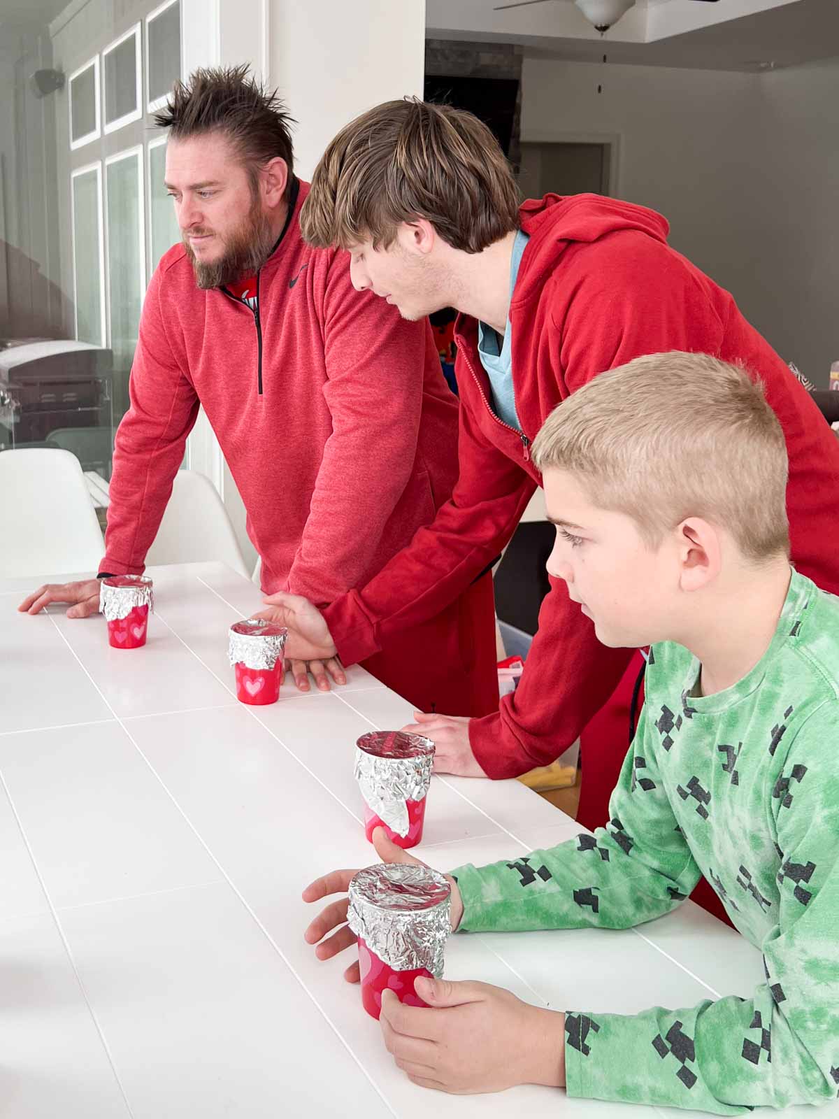 boys standing around plastic cups on a table