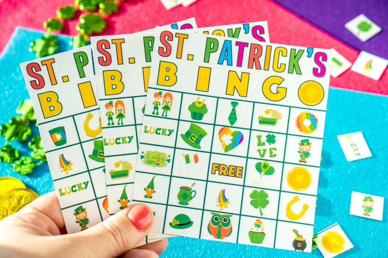 A hand holding up three St. Patrick's Day bingo cards