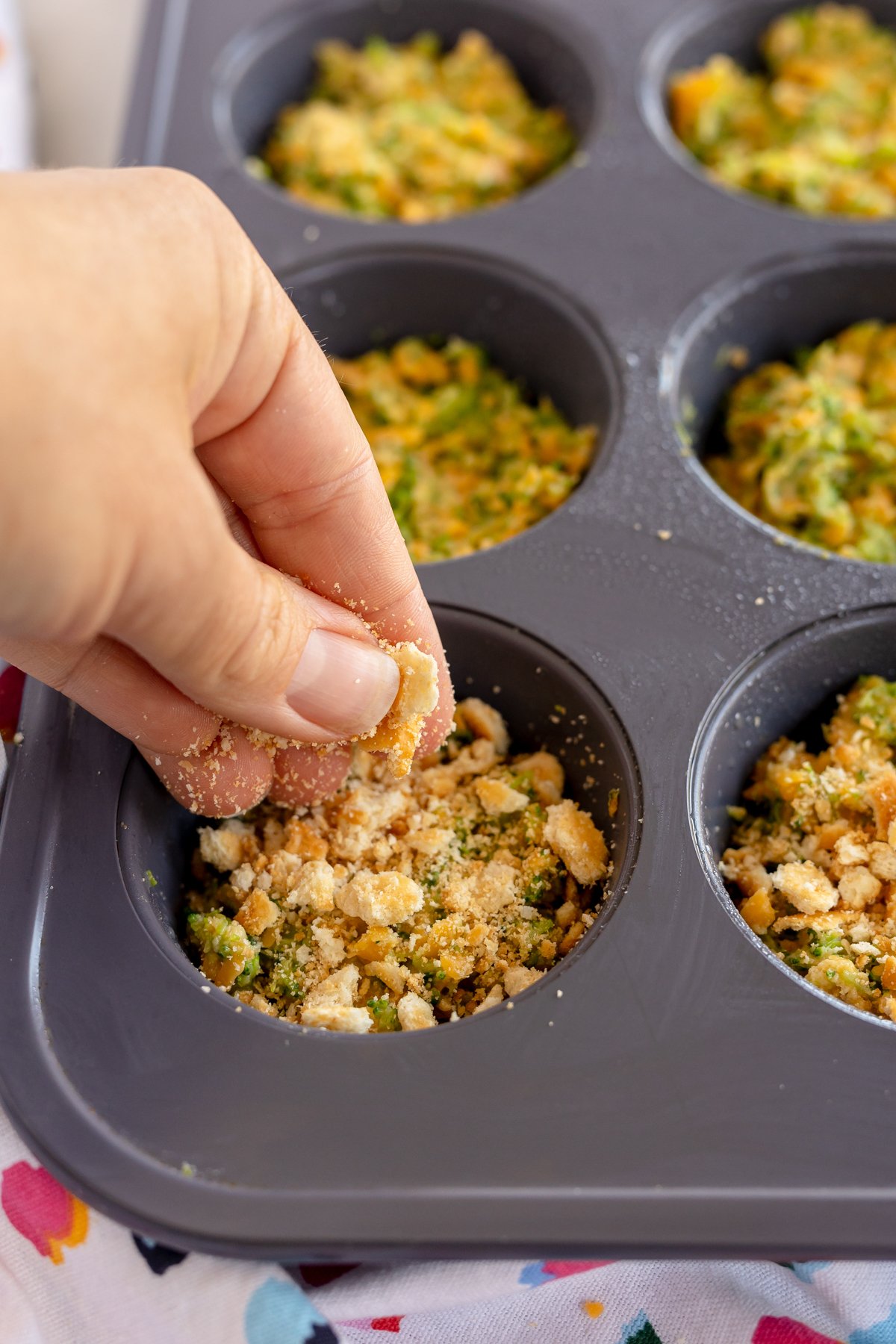 hand sprinkling ritz crackers on broccoli bites