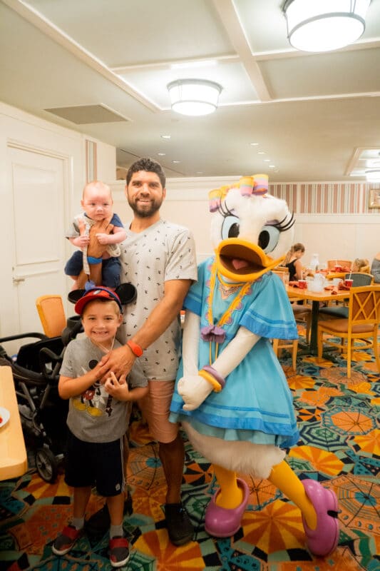 Family standing with Daisy Duck in blue dress