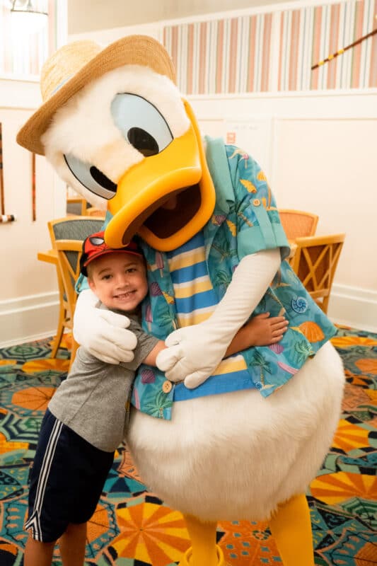 Boy hugging Donald Duck in a blue outfit