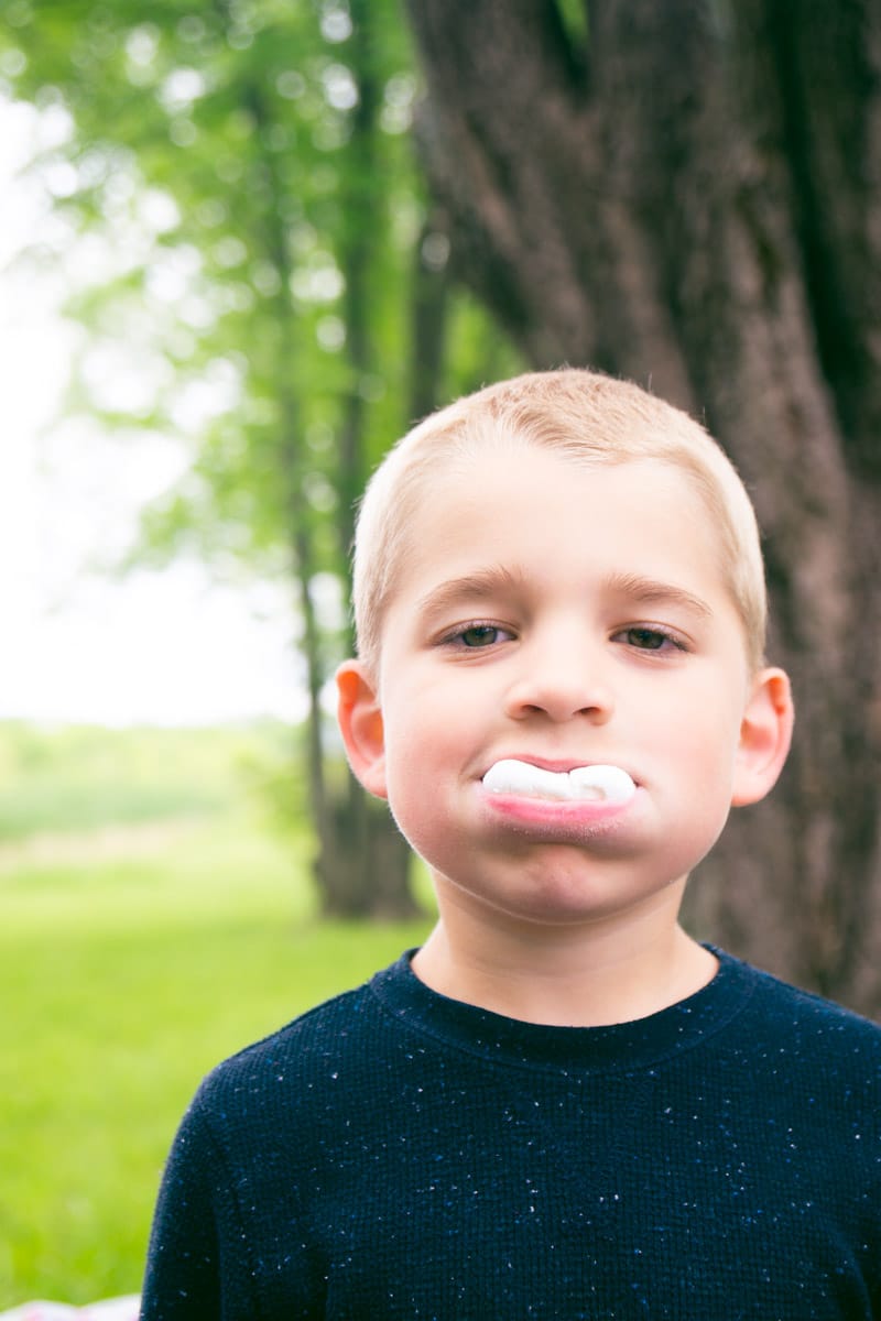 Kid with a marshmallow from a s'mores bar